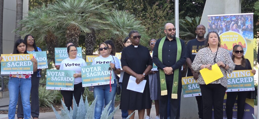 Supporters holding campaign signs written _Voting is Sacred_ in English and Spanish outside the Kern County Courthouse for the _Voting is Sacred_ press conference on Wednesday, Oct. 7 (Photo Credit: Cecil Egbele)